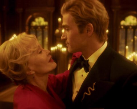 Due figure in una sala illuminata da luci dorate in American Horror Story 13x09