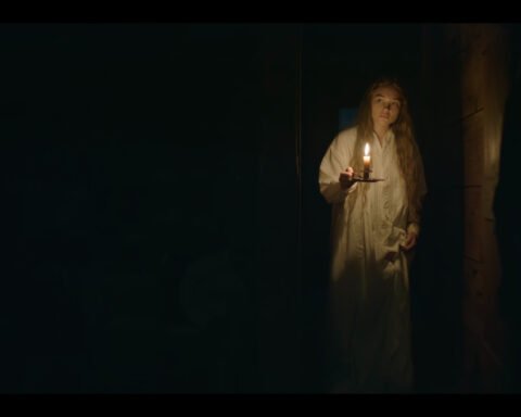 Giovane donna in camicia da notte bianca con una candela accesa in una stanza buia di East Of Eden 1x02